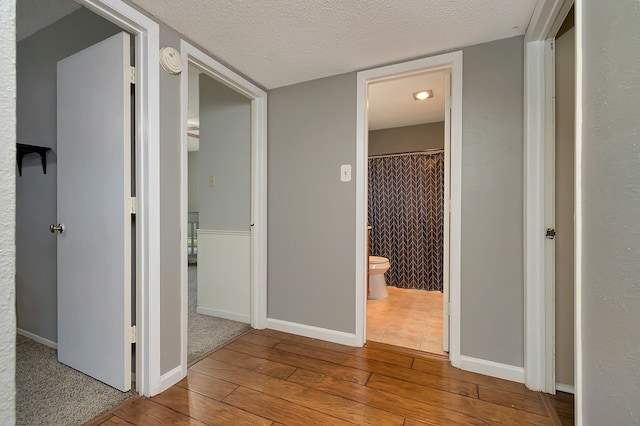 hallway with a textured ceiling and light wood-type flooring