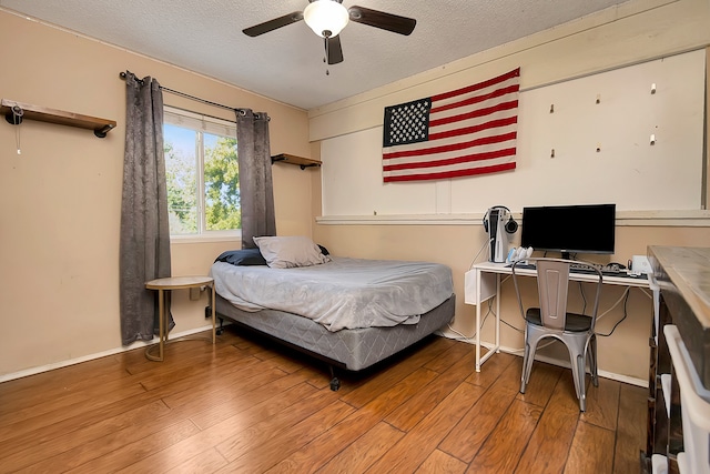 bedroom with ceiling fan, hardwood / wood-style floors, and a textured ceiling