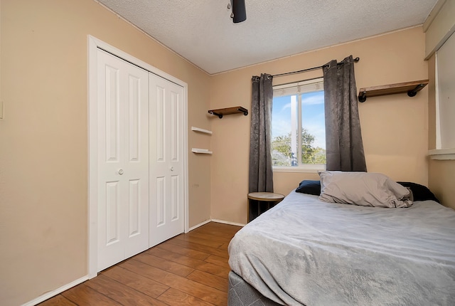 bedroom with a textured ceiling, wood-type flooring, ceiling fan, and a closet