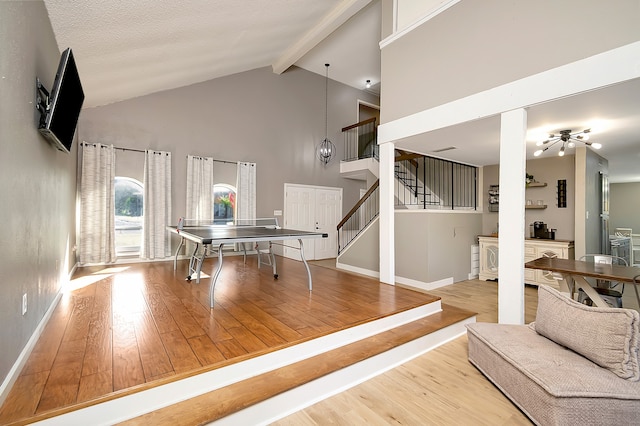 interior space featuring a fireplace, beam ceiling, hardwood / wood-style floors, and high vaulted ceiling