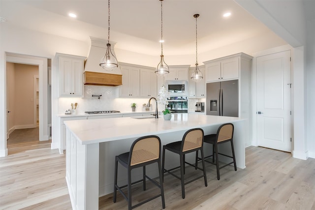 kitchen featuring sink, a large island with sink, light hardwood / wood-style floors, and stainless steel appliances