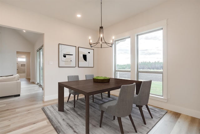 dining area featuring a chandelier, light wood-type flooring, and vaulted ceiling