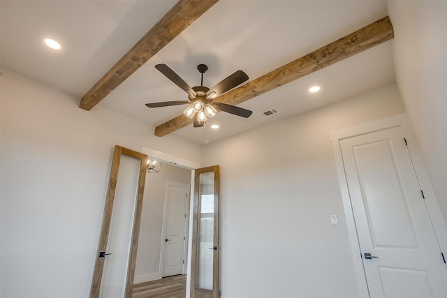 unfurnished bedroom featuring beamed ceiling, ceiling fan, and light hardwood / wood-style flooring