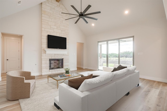 living room with a fireplace, ceiling fan, light wood-type flooring, and high vaulted ceiling