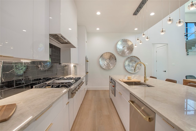 kitchen with light wood-type flooring, sink, white cabinetry, hanging light fixtures, and stainless steel appliances