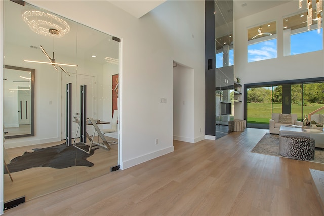 living room featuring an inviting chandelier, a wealth of natural light, a towering ceiling, and wood-type flooring