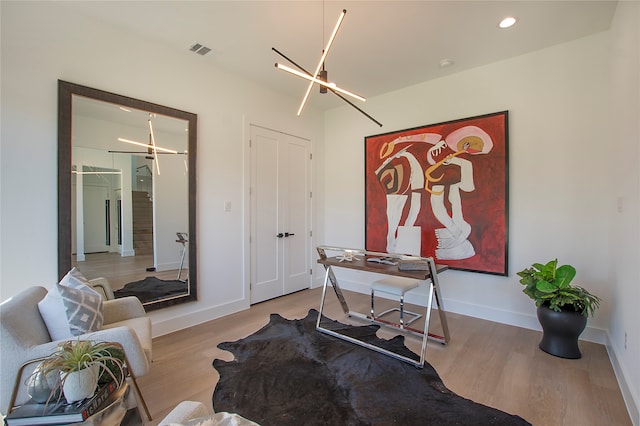 office with light hardwood / wood-style flooring and a chandelier