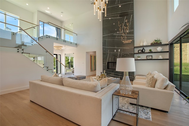 living room featuring a notable chandelier, light hardwood / wood-style floors, a towering ceiling, and a wealth of natural light