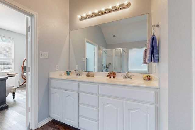 bathroom featuring walk in shower, vaulted ceiling, wood-type flooring, and vanity