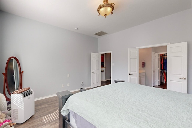 bedroom with a closet, dark hardwood / wood-style flooring, and a walk in closet