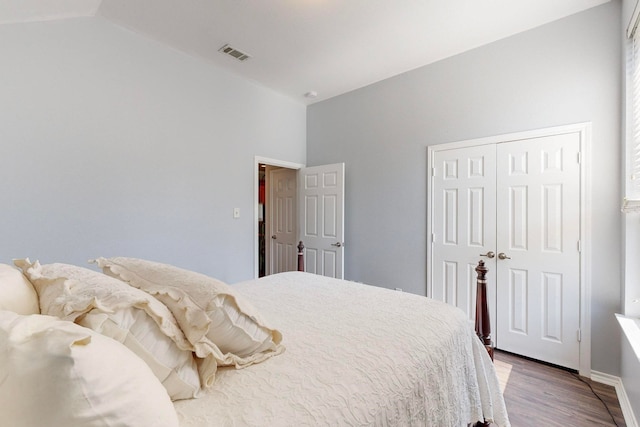 bedroom with hardwood / wood-style floors, vaulted ceiling, and a closet