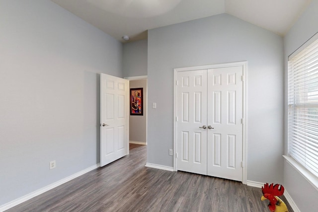 unfurnished bedroom with dark wood-type flooring, a closet, and lofted ceiling