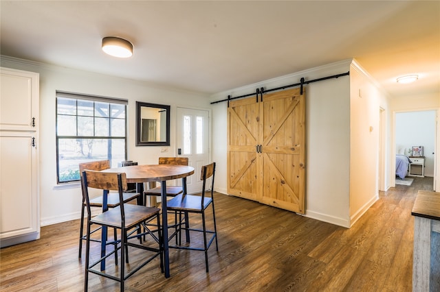 dining room with dark hardwood / wood-style floors, a barn door, and crown molding