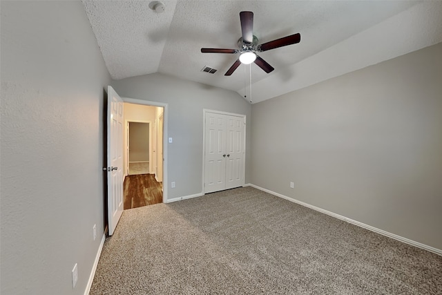 unfurnished bedroom with carpet flooring, a textured ceiling, ceiling fan, a closet, and lofted ceiling