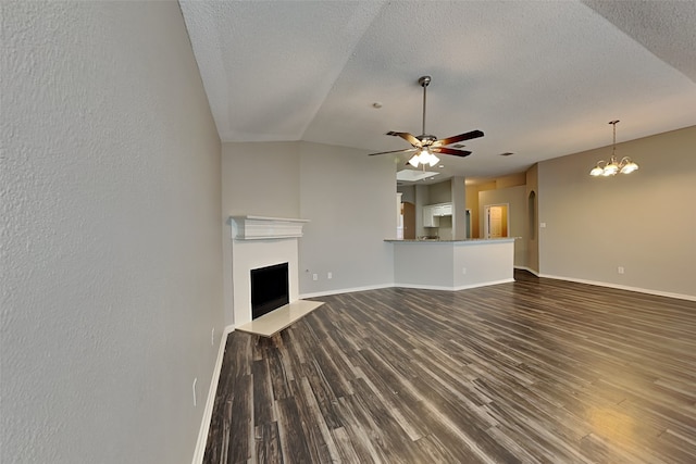 unfurnished living room with ceiling fan with notable chandelier, a textured ceiling, dark hardwood / wood-style flooring, and lofted ceiling