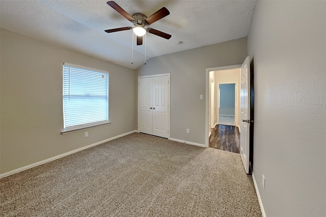 unfurnished bedroom with carpet, a textured ceiling, vaulted ceiling, and ceiling fan