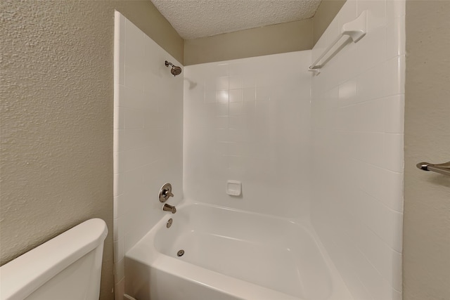 bathroom featuring a textured ceiling, toilet, and tiled shower / bath