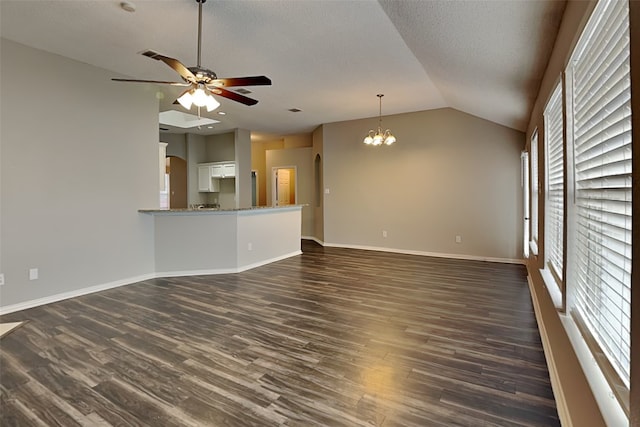 unfurnished living room featuring a textured ceiling, dark hardwood / wood-style floors, lofted ceiling, and ceiling fan with notable chandelier