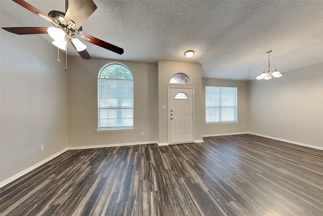 foyer entrance featuring a textured ceiling, ceiling fan with notable chandelier, dark hardwood / wood-style floors, and vaulted ceiling