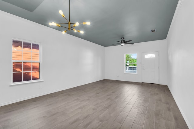 unfurnished room with ceiling fan with notable chandelier, crown molding, and hardwood / wood-style flooring