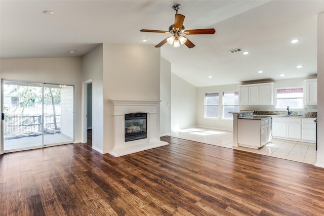 unfurnished living room with sink, light hardwood / wood-style floors, plenty of natural light, and ceiling fan