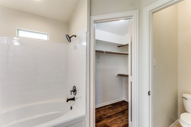 bathroom with hardwood / wood-style floors, shower / bathtub combination, and toilet