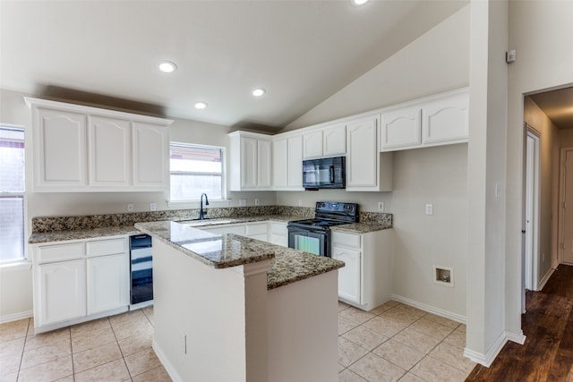 kitchen featuring vaulted ceiling, black appliances, stone countertops, a center island, and white cabinetry