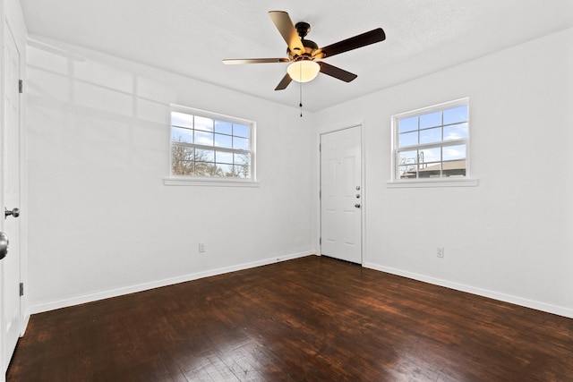 spare room featuring a textured ceiling, ceiling fan, a healthy amount of sunlight, and dark hardwood / wood-style flooring