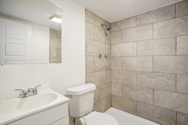 bathroom featuring toilet, vanity, and tiled shower