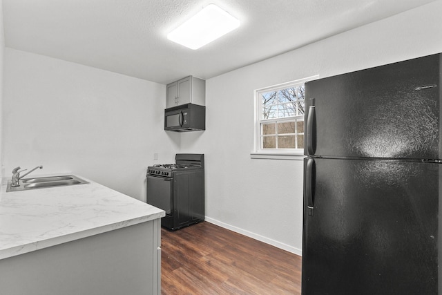 kitchen featuring black appliances, gray cabinetry, dark hardwood / wood-style flooring, and sink