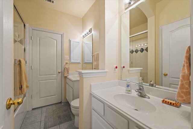 full bathroom featuring tile patterned flooring, vanity, toilet, and bath / shower combo with glass door