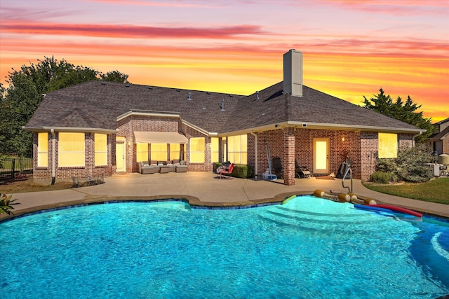 pool at dusk with a patio area