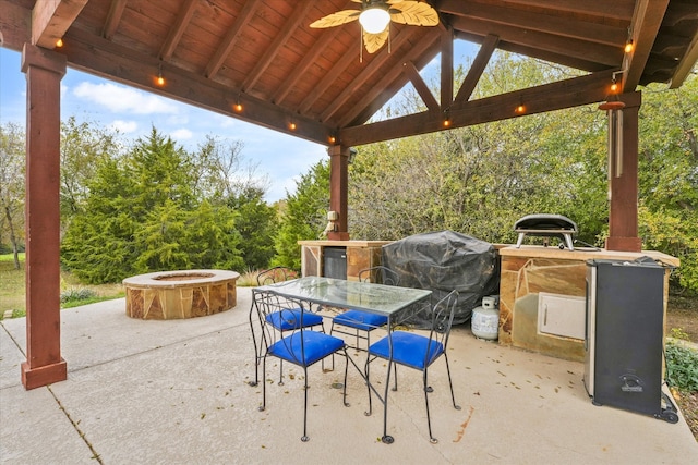 view of patio featuring a gazebo, ceiling fan, a grill, and an outdoor fire pit