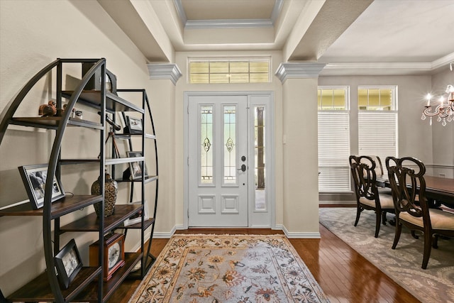 entryway featuring ornamental molding, dark wood-type flooring, and an inviting chandelier