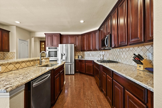 kitchen featuring appliances with stainless steel finishes, dark hardwood / wood-style flooring, a textured ceiling, and sink