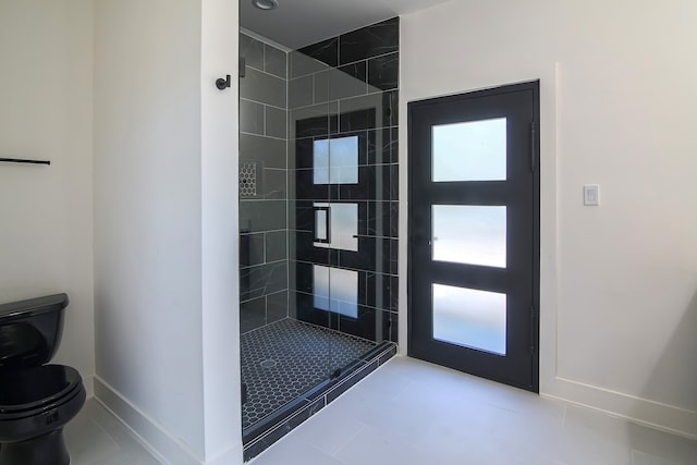 bathroom with tiled shower, tile patterned flooring, and toilet