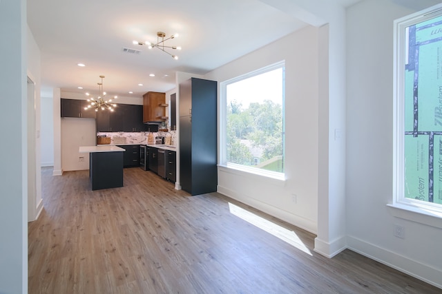 kitchen with a center island, hanging light fixtures, tasteful backsplash, light hardwood / wood-style flooring, and a chandelier