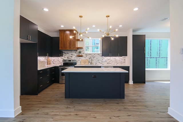 kitchen with stainless steel electric range oven, a kitchen island, light hardwood / wood-style floors, and decorative light fixtures