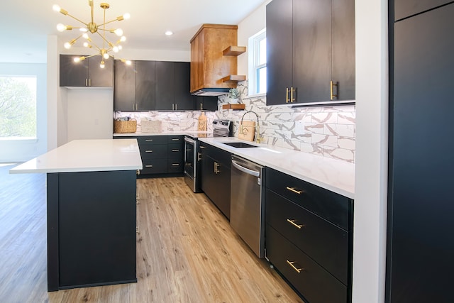 kitchen featuring a center island, sink, stainless steel appliances, light hardwood / wood-style flooring, and decorative light fixtures