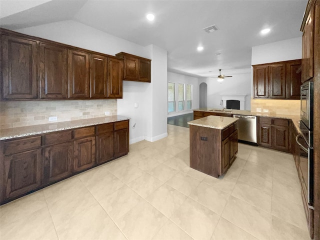 kitchen with appliances with stainless steel finishes, backsplash, a kitchen island, ceiling fan, and sink