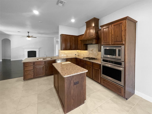 kitchen with sink, kitchen peninsula, stainless steel appliances, ceiling fan, and premium range hood