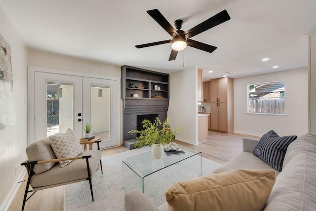 living area with light wood finished floors, baseboards, french doors, a fireplace, and recessed lighting