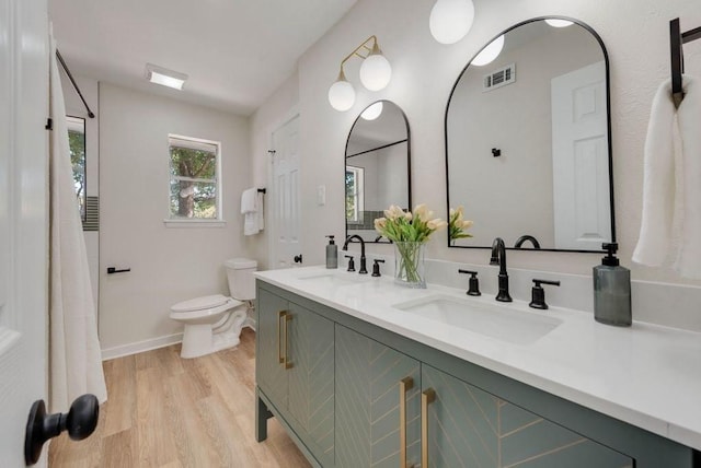 full bathroom featuring toilet, visible vents, a sink, and wood finished floors