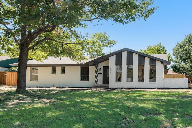 view of front facade featuring brick siding, fence, and a front yard