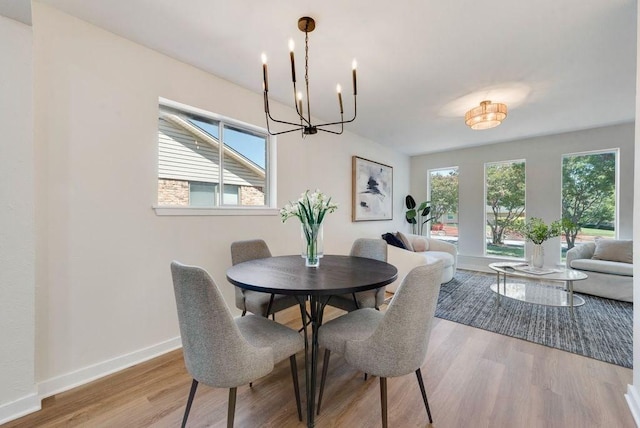 dining room with a chandelier, baseboards, and wood finished floors