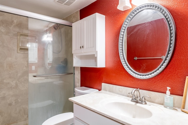 bathroom featuring vanity, a shower with shower door, and toilet