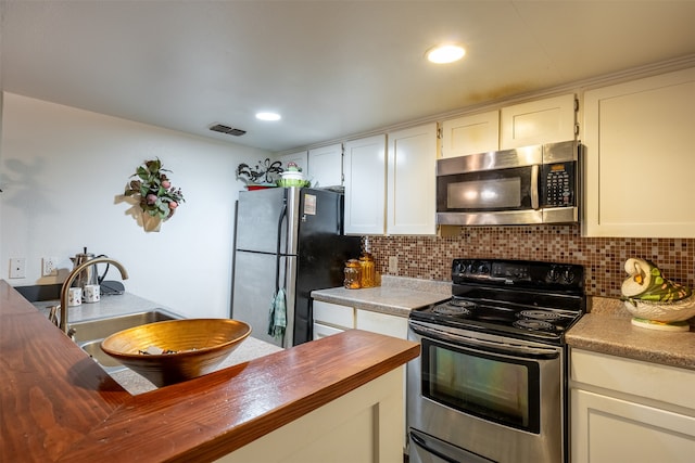 kitchen featuring backsplash, white cabinetry, appliances with stainless steel finishes, and wooden counters