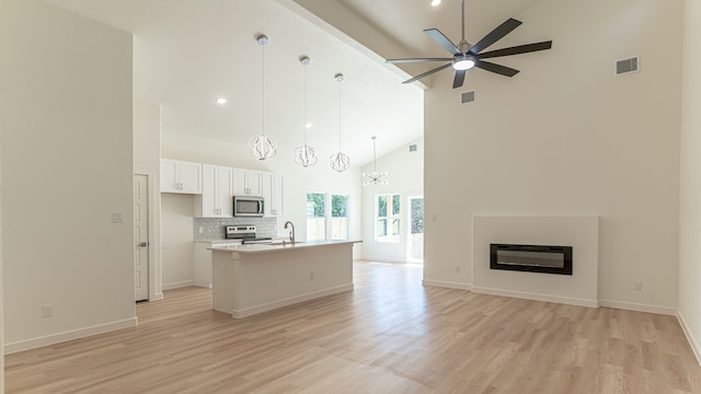 kitchen with white cabinetry, high vaulted ceiling, ceiling fan with notable chandelier, pendant lighting, and stainless steel appliances