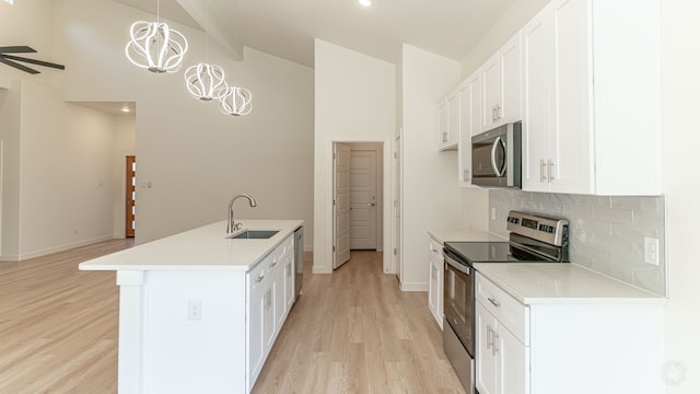 kitchen featuring white cabinetry, stainless steel appliances, light hardwood / wood-style flooring, decorative light fixtures, and sink