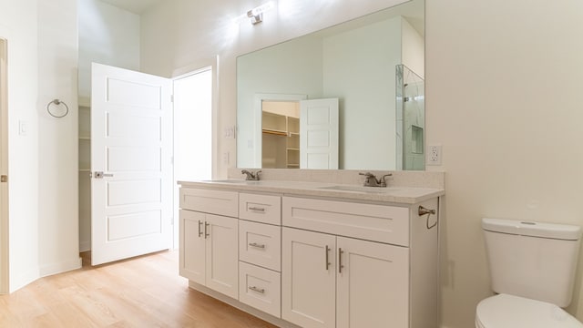 bathroom featuring hardwood / wood-style floors, walk in shower, vanity, and toilet